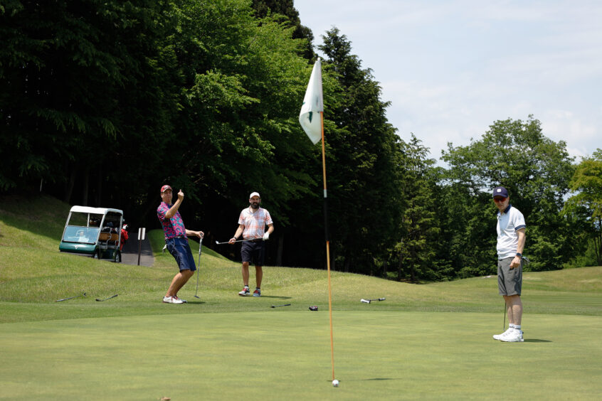 Participants enjoy playing and engaging on the green at the all-TUJ golf event. Photo by Anthony Smith (TUJ student)