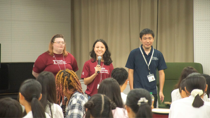 Three TUJ student workers giving a presentation in front of high school students.